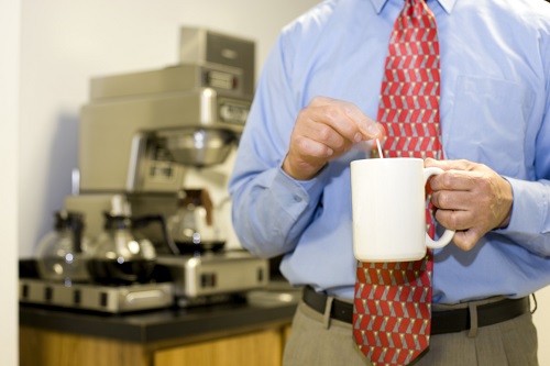 Büromitarbeiter rührt Kaffee um